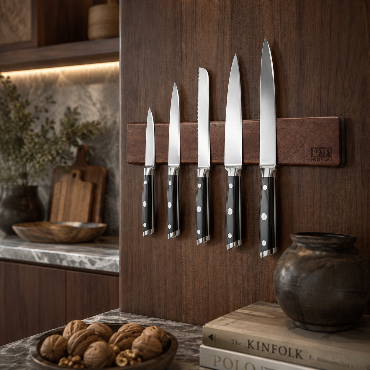 Walnut magnetic knife holder mounted on dark wood cabinetry with five stainless steel kitchen knives.
